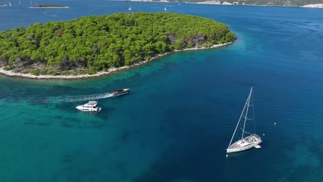 pleasure yachts near beautiful lush island in turquoise sea aerial