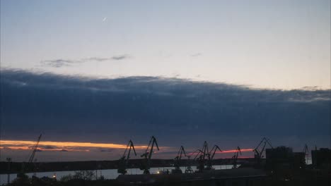 beautiful sunset timelapse over harbor of klaipeda. harbor cranes and ship movement.