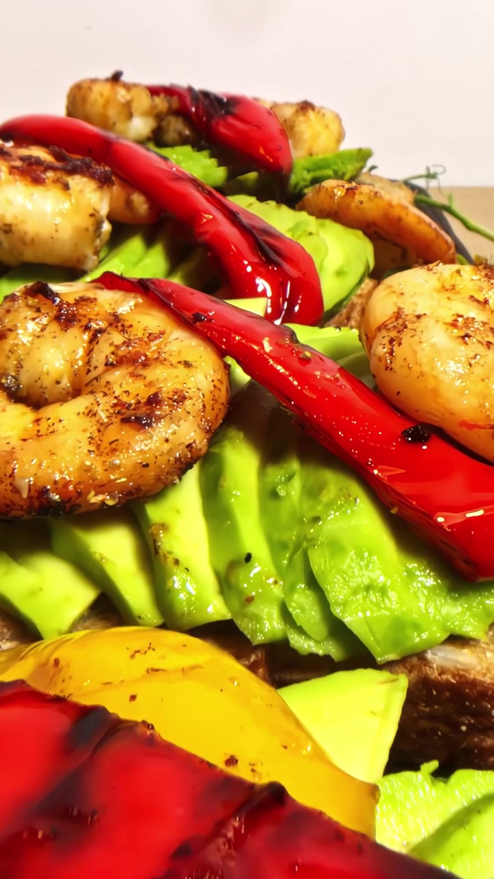 Gamberi succulenti e peperoni vivaci su avocado cremoso adagiati su pane tostato, creando una scena che fa venire l'acquolina in bocca.