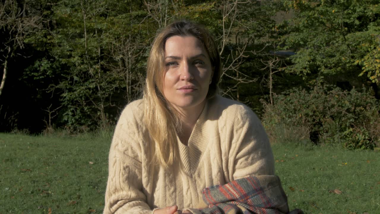 mulher criativa a escrever na natureza a olhar para a câmara.