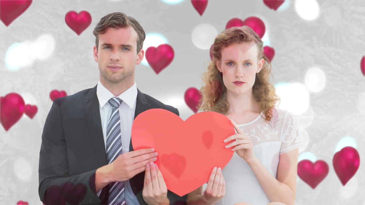 새로 결혼 한 부부는 큰 빨간 심장을 함께 들고 있습니다.