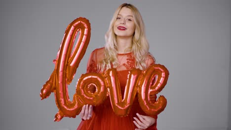 mujer de vestido rojo con globos de amor