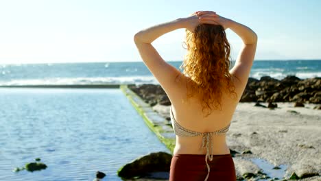 woman standing with hands on hair at beach 4k