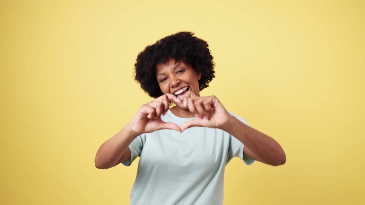 Donna afroamericana felice che fa il gesto del cuore e sorride