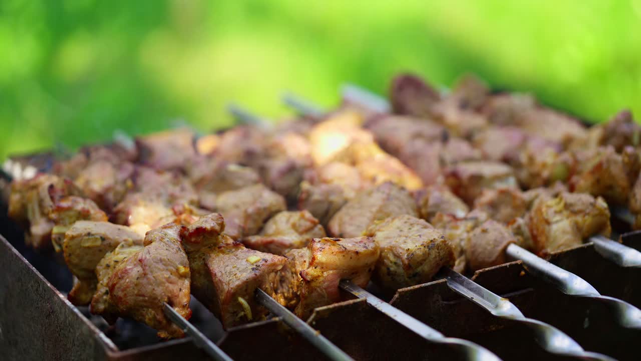 Delicious kebab outdoors. Preparation of pork meat on grill. Skewers with barbecue in mangal on green background.