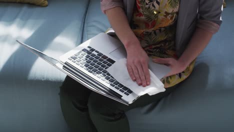 Mid-section-of-woman-wiping-her-laptop-with-a-tissue