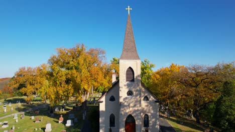 colorful autumn trees with small catholic church and cemetry drone