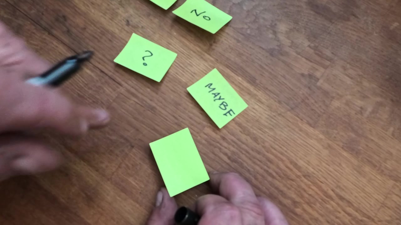 Hand writing messages on yellow sticky post-it note in brainstorming thought process goal