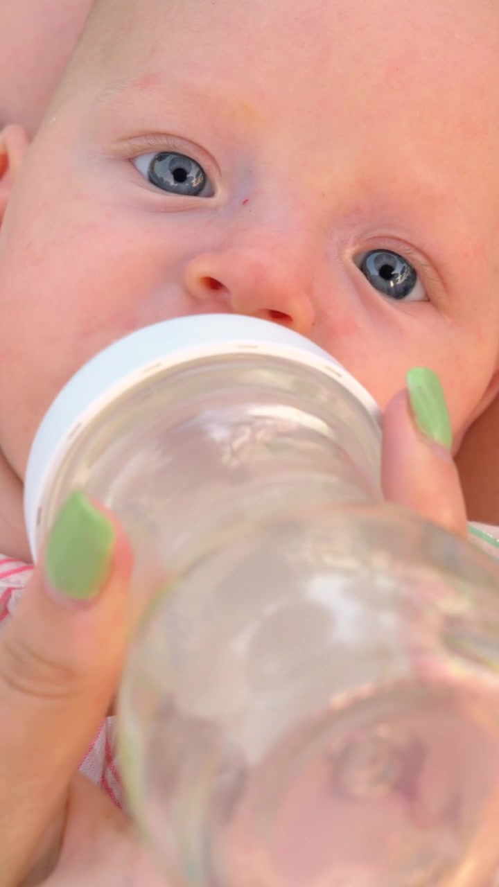 Madre che dà da bere acqua alla figlia piccola dal biberon