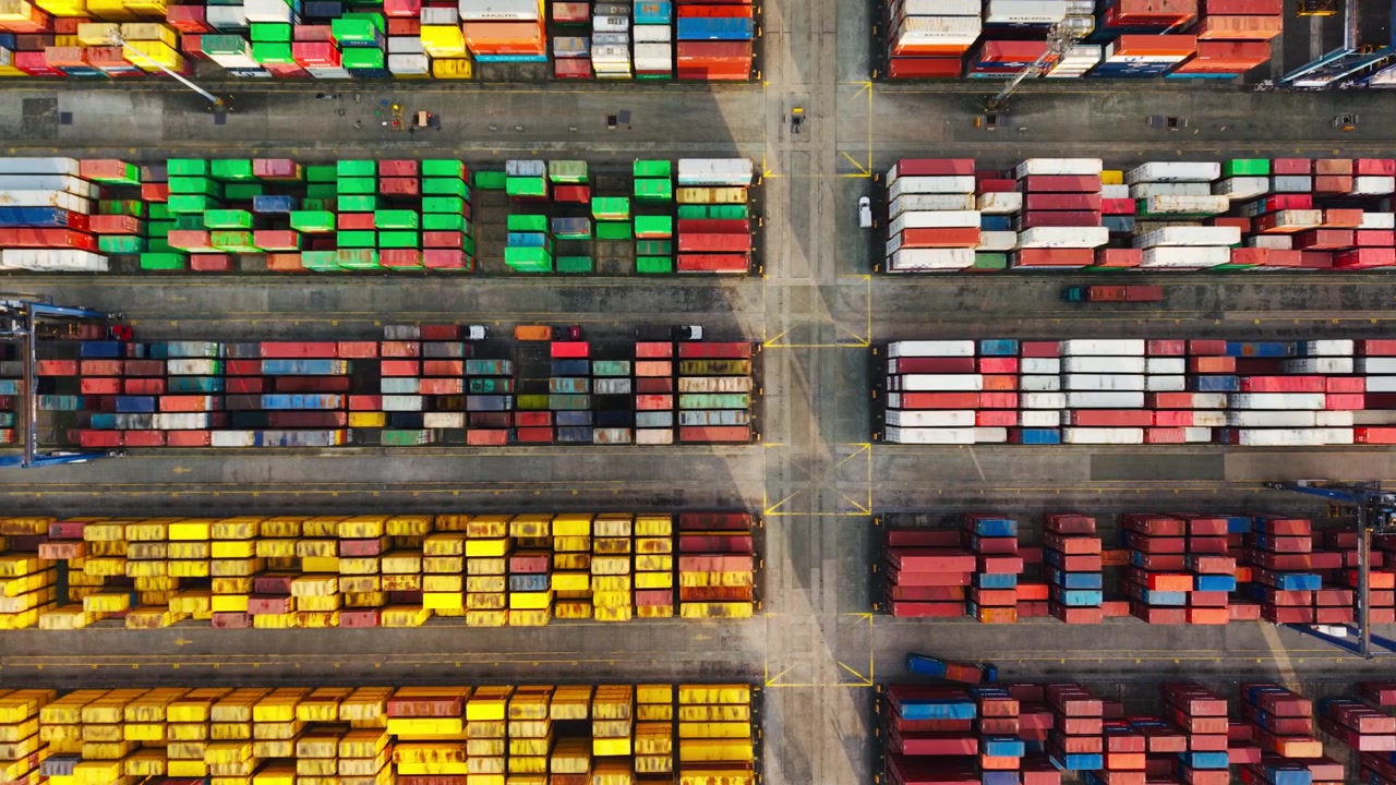 Top down aerial reveals colorful cargo rows as the drone glides at sunset