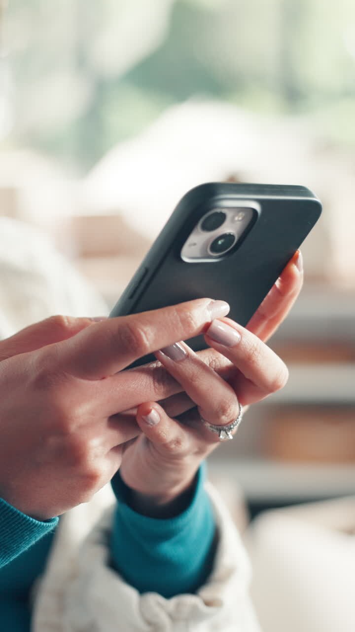 Nahaufnahme von Händen, die auf einem Smartphone scrollen und es benutzen