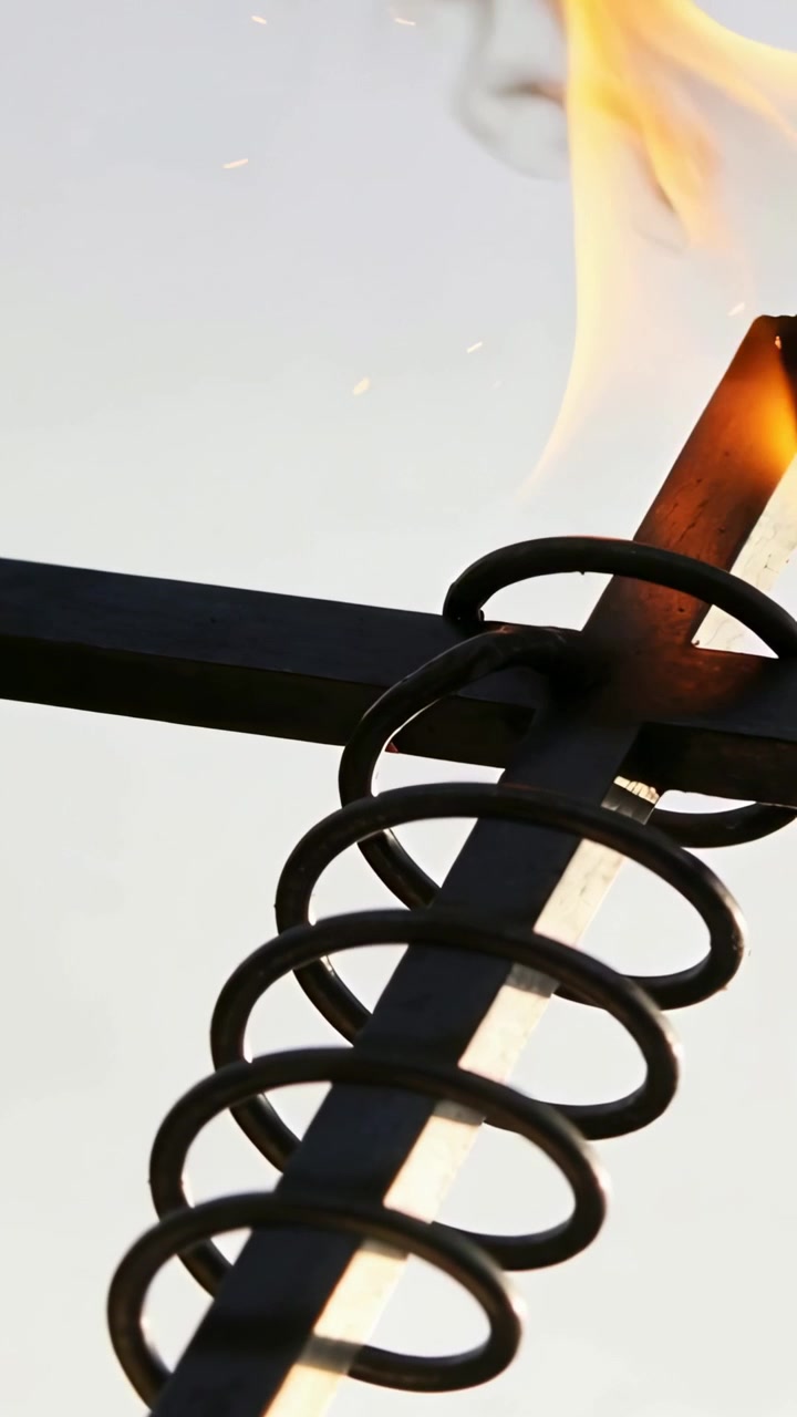 Vertical video: Appearing flame on wick growing, heating coil on crossbar and rod, smoke drifting