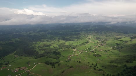 Sirnea-village-nestled-among-lush-hills-under-a-cloudy-sky,-daylight,-aerial-view