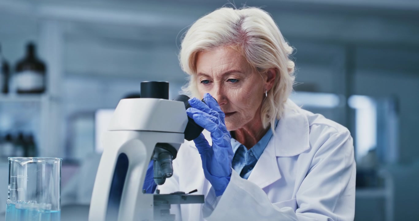 Senior Female Scientist Using Microscope in Laboratory