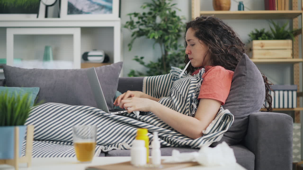 Woman sick at home using laptop