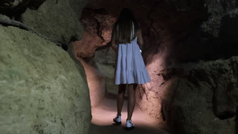 a lonely girl walks in a cave underground caves and tunnels girl tourist walks around the cave and examines it underground caves and tunnels