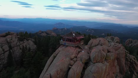 Luftaufnahme-Einer-Frau,-Die-Auf-Einer-360-Grad-Terrasse-Eines-Gebäudes-Auf-Einem-Hügel-Läuft-Und-Einen-Atemberaubenden-Blick-Auf-Die-Bergkette-Bietet