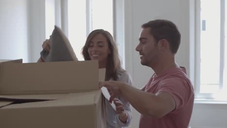 young couple opening box with pillows and smiling