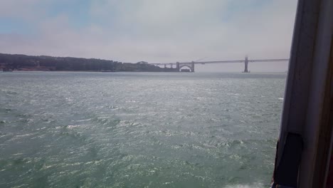 gimbal shot from the side of a moving boat as it approaches the golden gate bridge enveloped in fog
