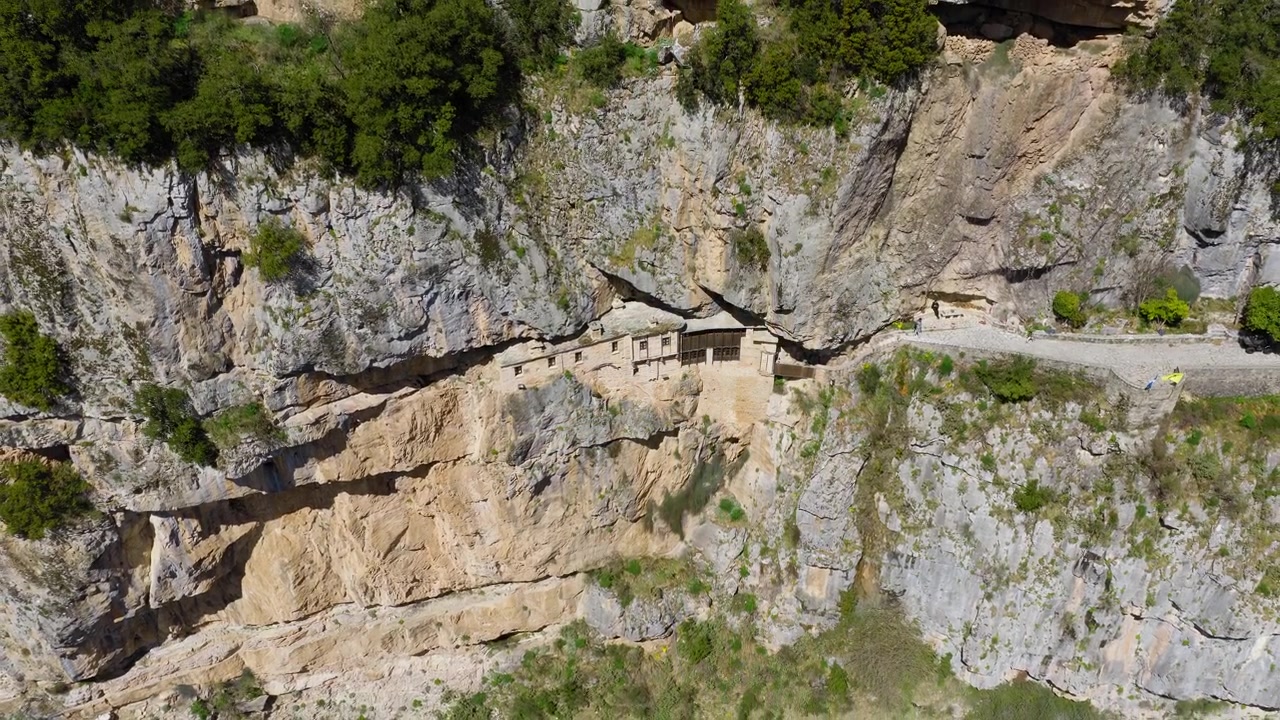 Ampia ascesa orbitale con drone del Sacro Monastero di Kipinas sotto imponenti scogliere in Grecia, ripresa aerea