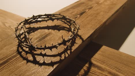 concepto religioso filmado con corona de espinas y cruz de madera en un charco de luz