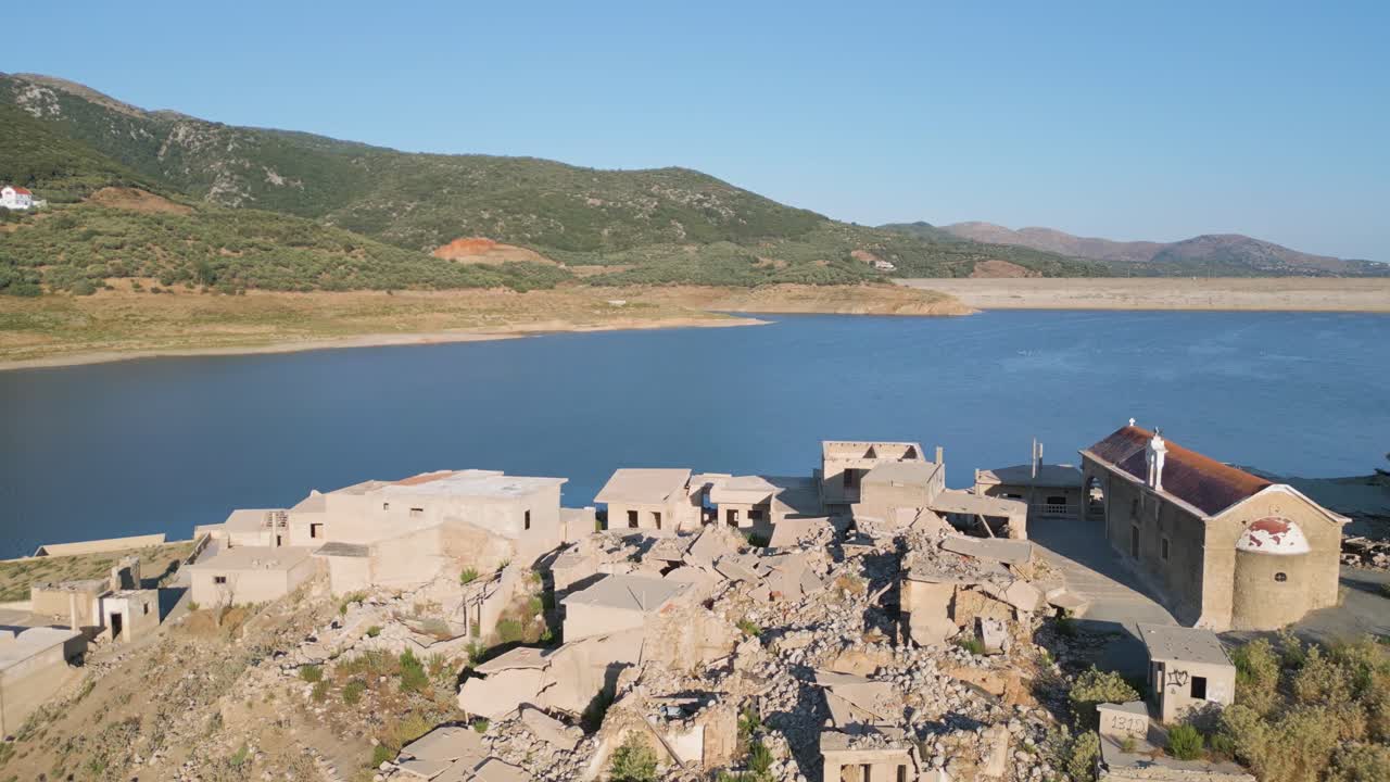 A captivating drone reveal of the submerged village of Sfendili on Aposelemis Lake’s shore in Crete, showcasing partially flooded buildings and stunning reflections