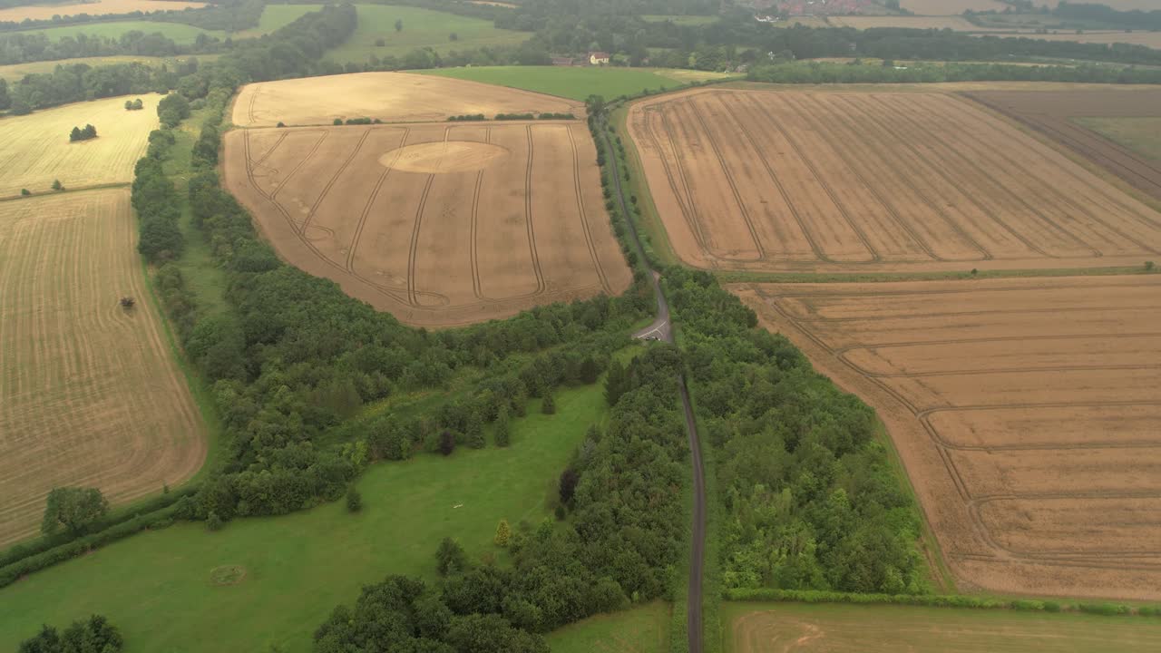 Rural farmland meadows aerial view heading towards golden disc remains of harvested crop circle