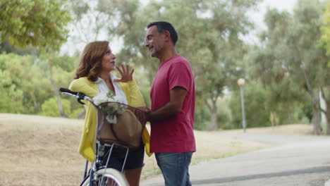 caucasian lovers standing next to bike, looking at each other