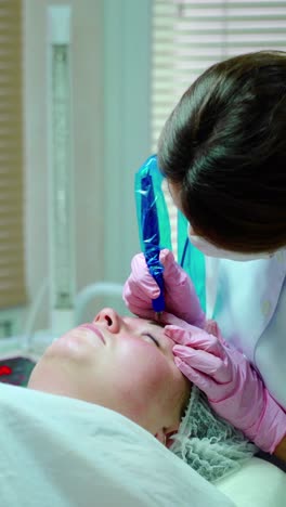 cosmetologist applying permanent make up on eyebrows