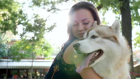 happy girl have fun and hugging husky in backlight outdoors close-up