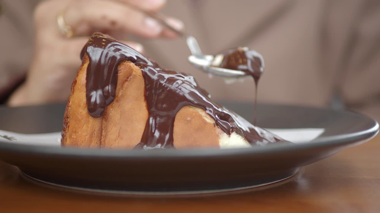 Close-up de mão comendo cheesecake de chocolate com uma colher