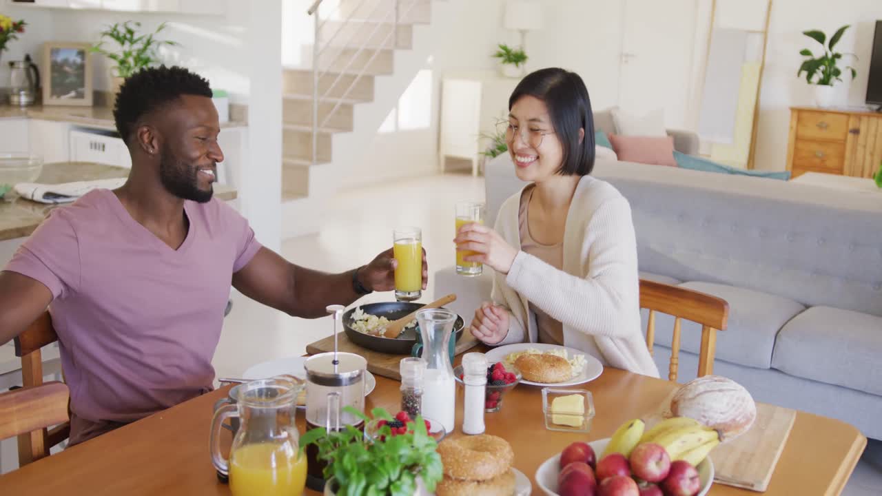 테이블 에 앉아 아침 식사를 하는 다양한 행복 한 부부