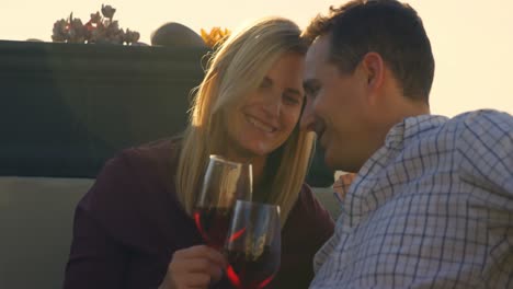pareja feliz tomando vino tinto en el balcón de su casa 4k