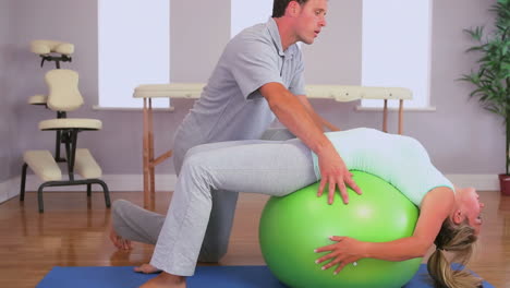 fisioterapeuta trabajando con un paciente en una pelota de ejercicio