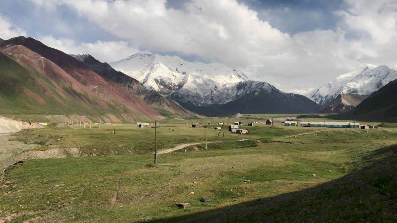 Arka planda bulutlarla kaplı dağ sırası ve "soğan çayırı" yakınındaki ana kamplarla birlikte Lenin Zirvesi ana kampı.