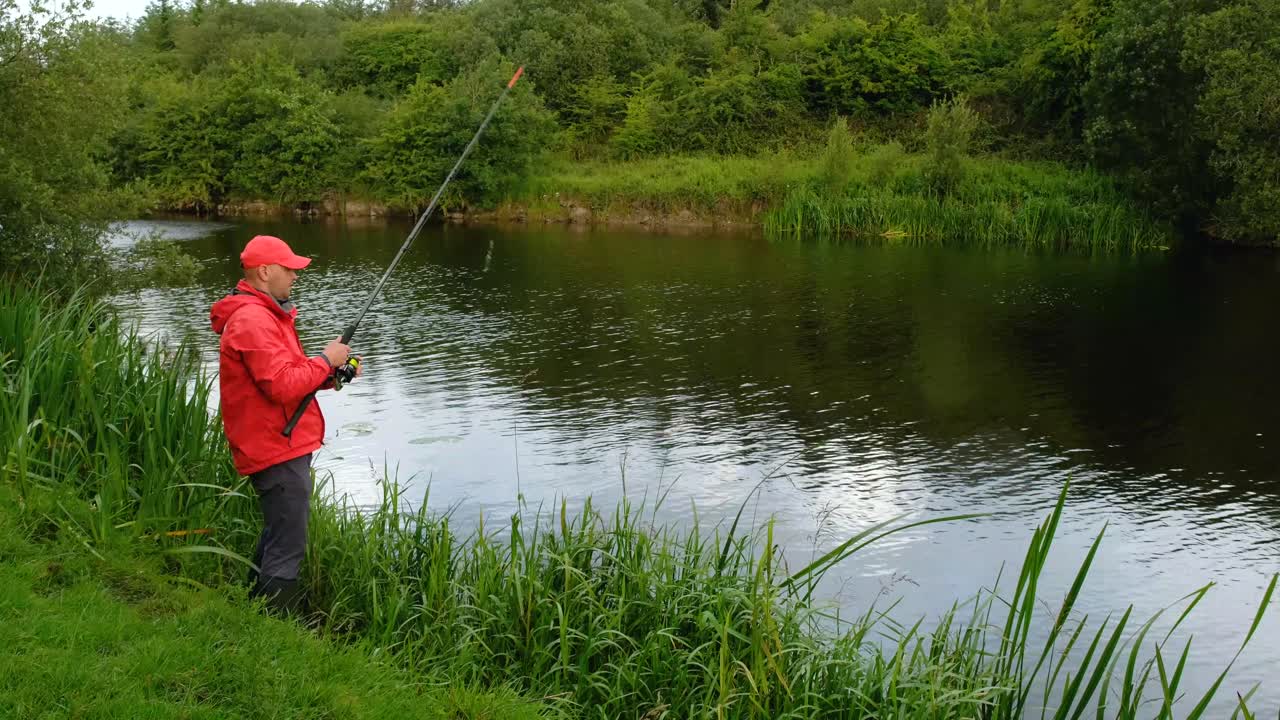Pemancing di tepi sungai dengan pancing di tangannya.