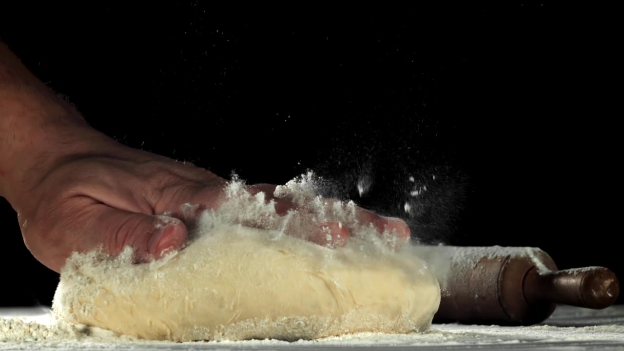 Slow Motion of Hand Sprinkling Flour on Dough for Baking