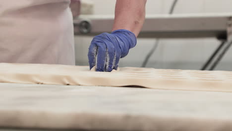 Die-Hand-Des-Bäckers-Im-Handschuh-Formt-Brotteig-In-Der-Backküche