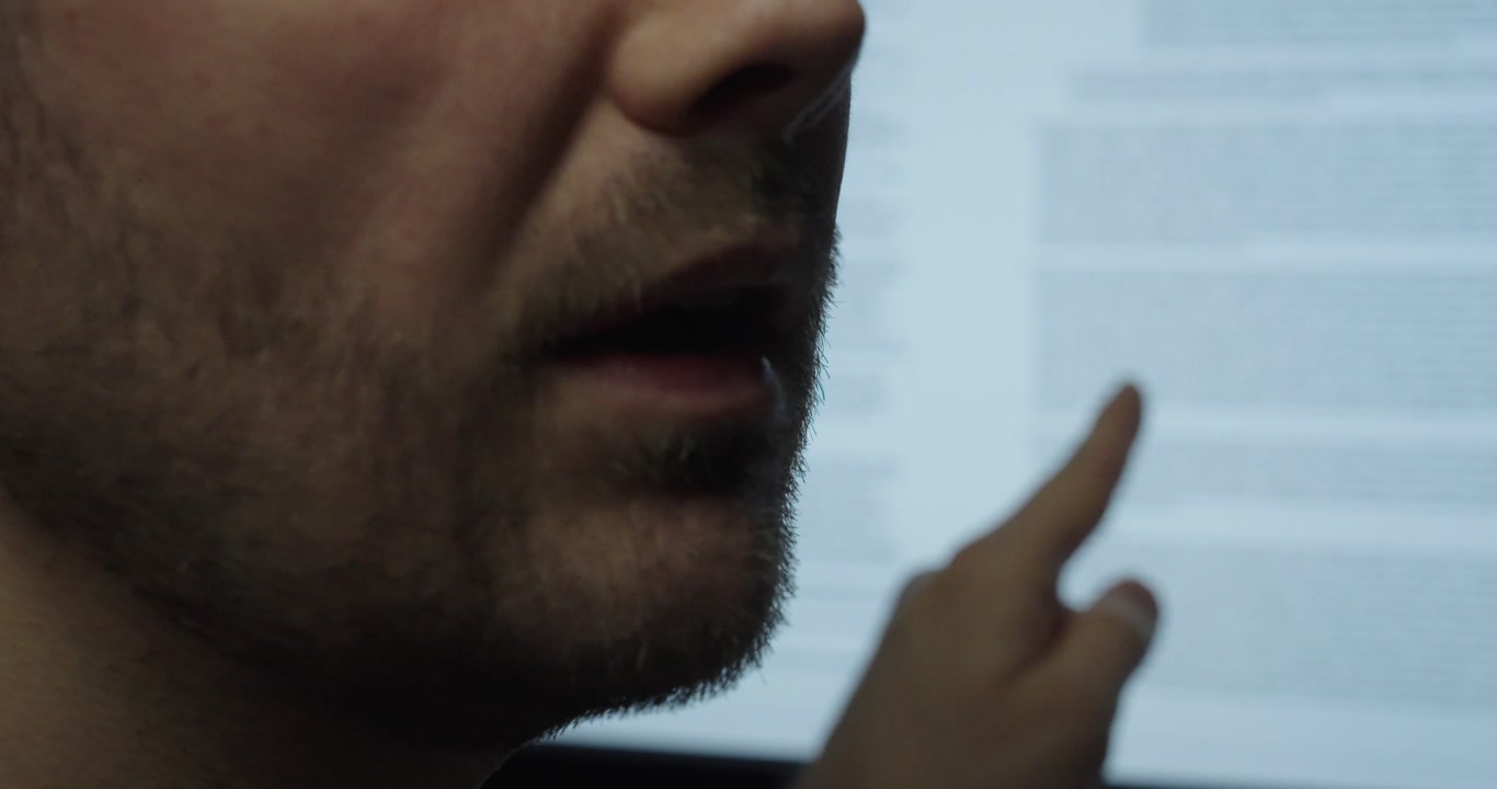 Close-up of a man explaining contract terms while pointing at a document on screen. Concept of agreement, legal review and business communication.