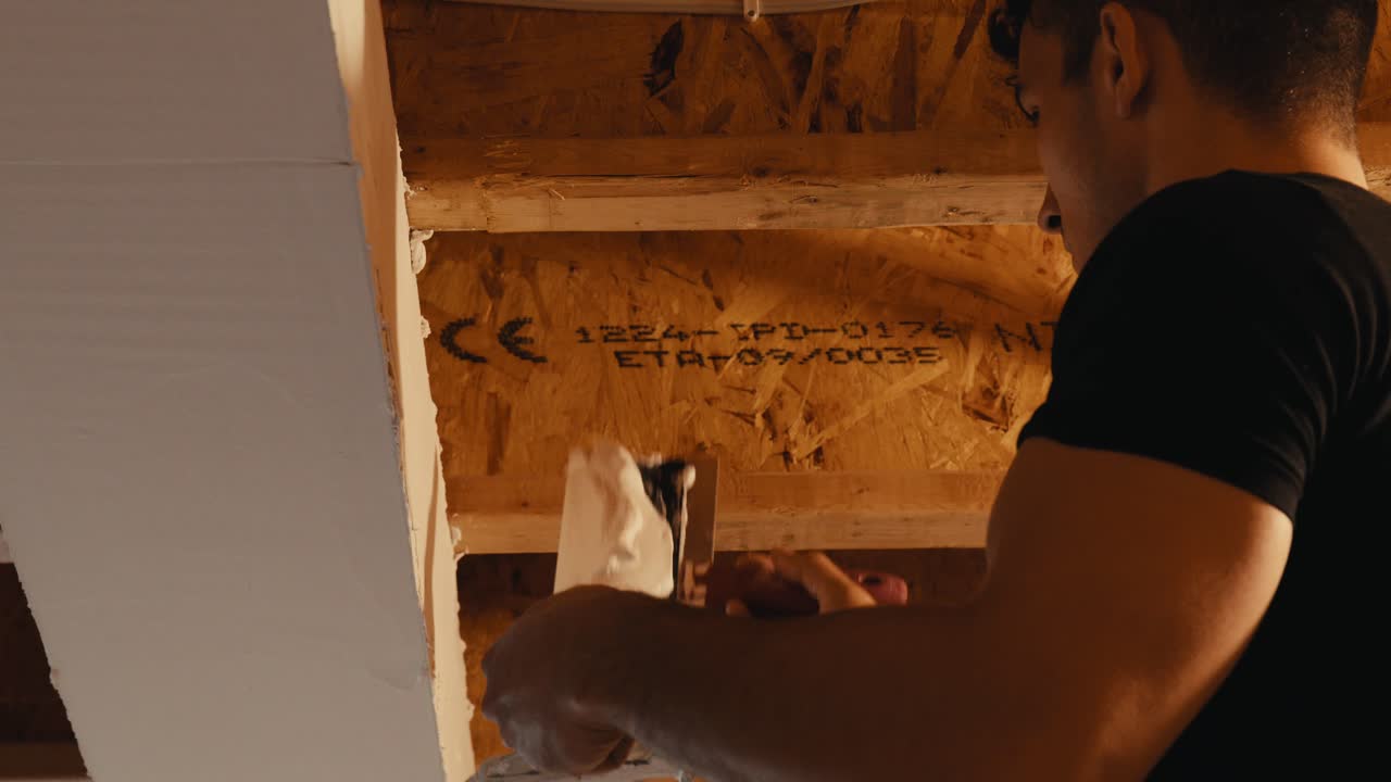 trabajador orientado al detalle grabando costuras de paneles de yeso para un acabado suave