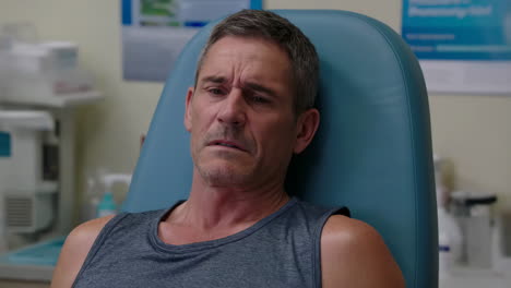 a man in a medical setting appears to be experiencing discomfort or pain
