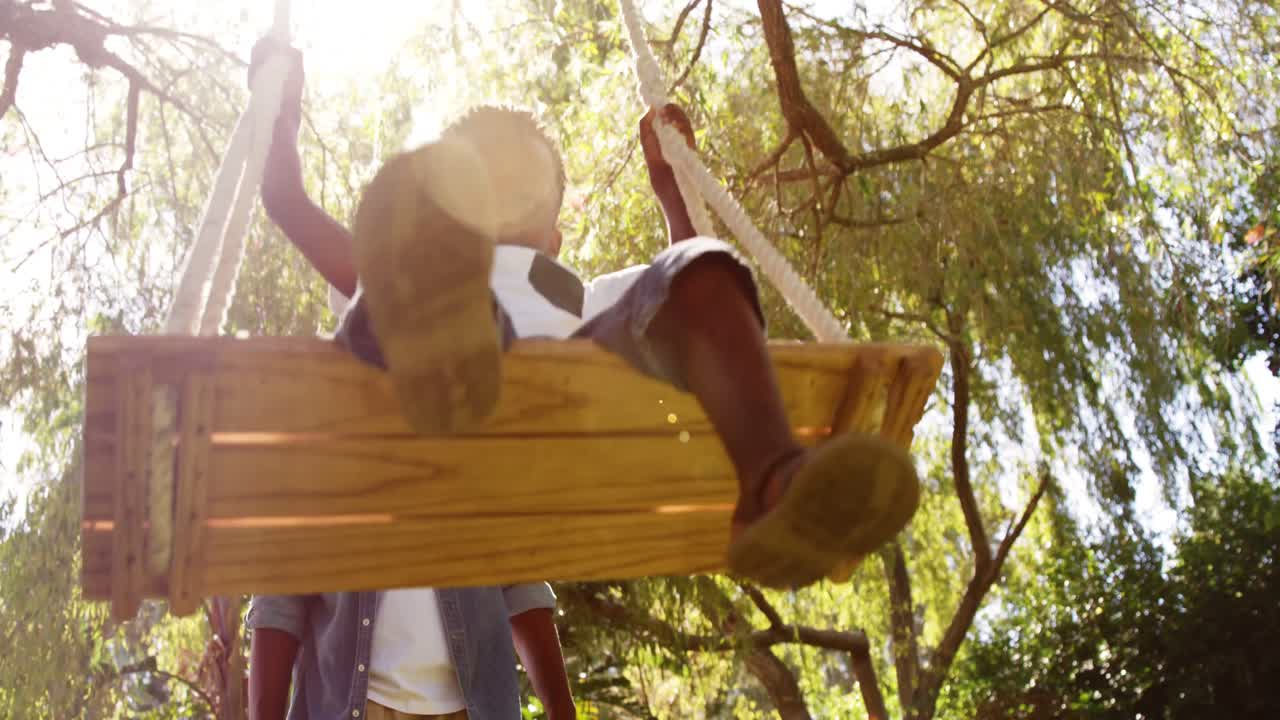 vista de bajo ángulo de un niño pequeño balanceándose con su padre