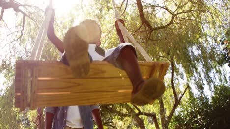 low angle view of little boy swinging with his father