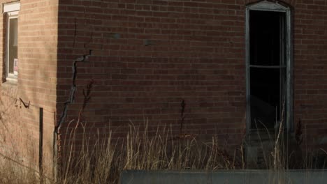 an abandoned broken brick building with hollow black empty windows