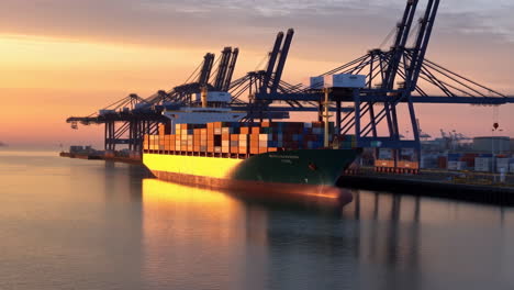 container ship docked at port at sunset