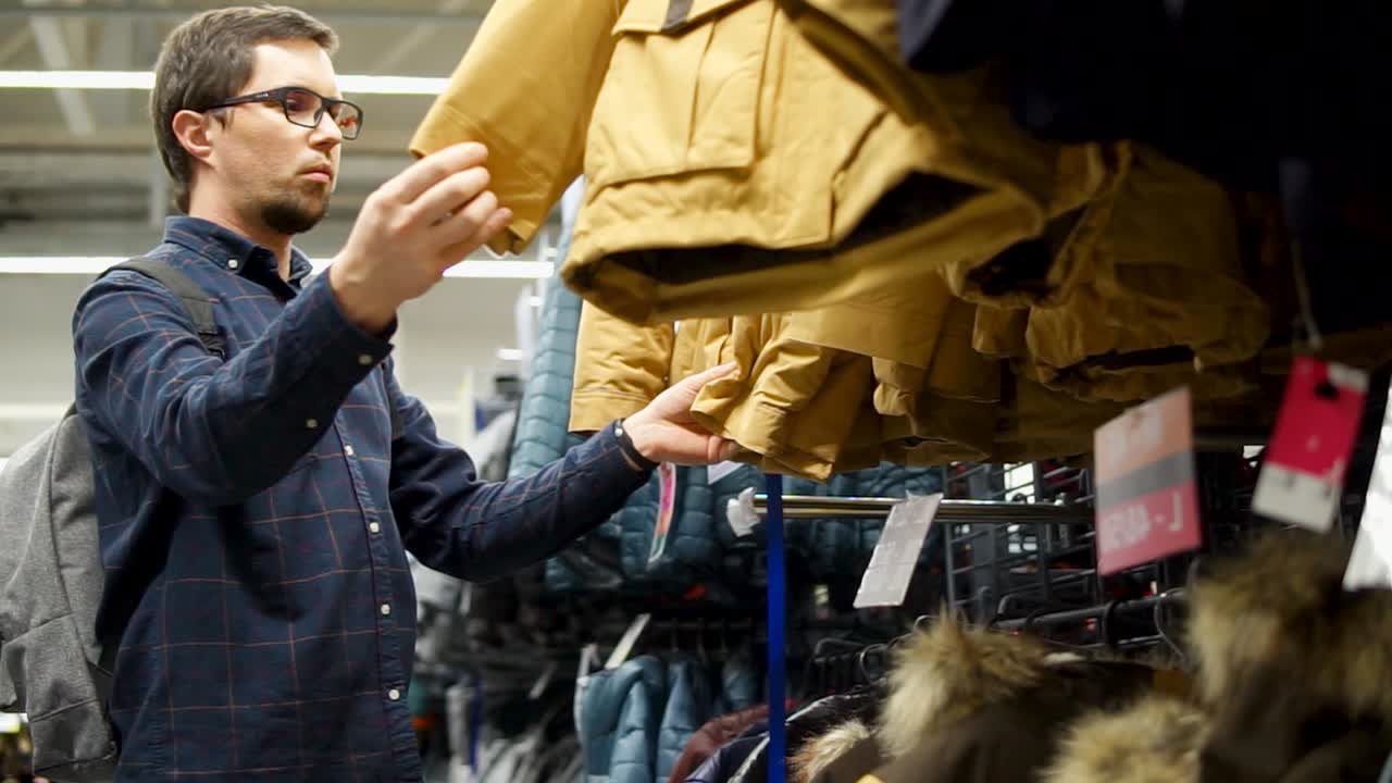 hombre comprando chaquetas en una tienda