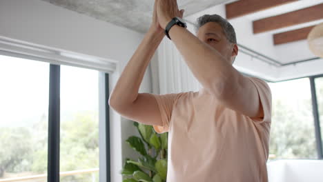 senior biracial man practicing yoga meditation at home