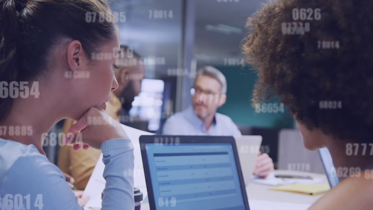 animación de múltiples números cambiantes contra dos mujeres diversas discutiendo sobre la computadora portátil en la oficina