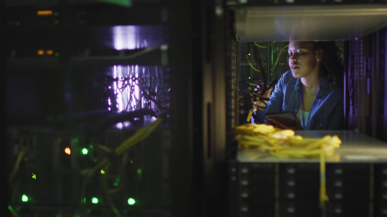 técnica informática afroamericana que usa una tableta trabajando en una sala de servidores de negocios