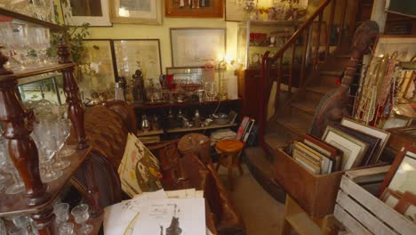 slow pan across antique shop full of vintage glasses, paintings, books, and staircase leading up